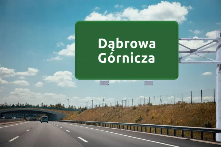 duży, zielony znak drogowy z nazwą Dąbrowa Górnicza, wiszący nad autostradą