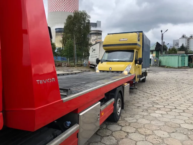 żółty bus wjeżdża na lawetę pomocy drogowej w Jaworznie