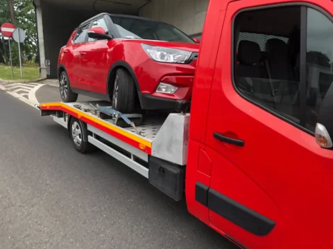 czerwone SsagYong załadowane na lawetę pomocy drogowej w Katowicach